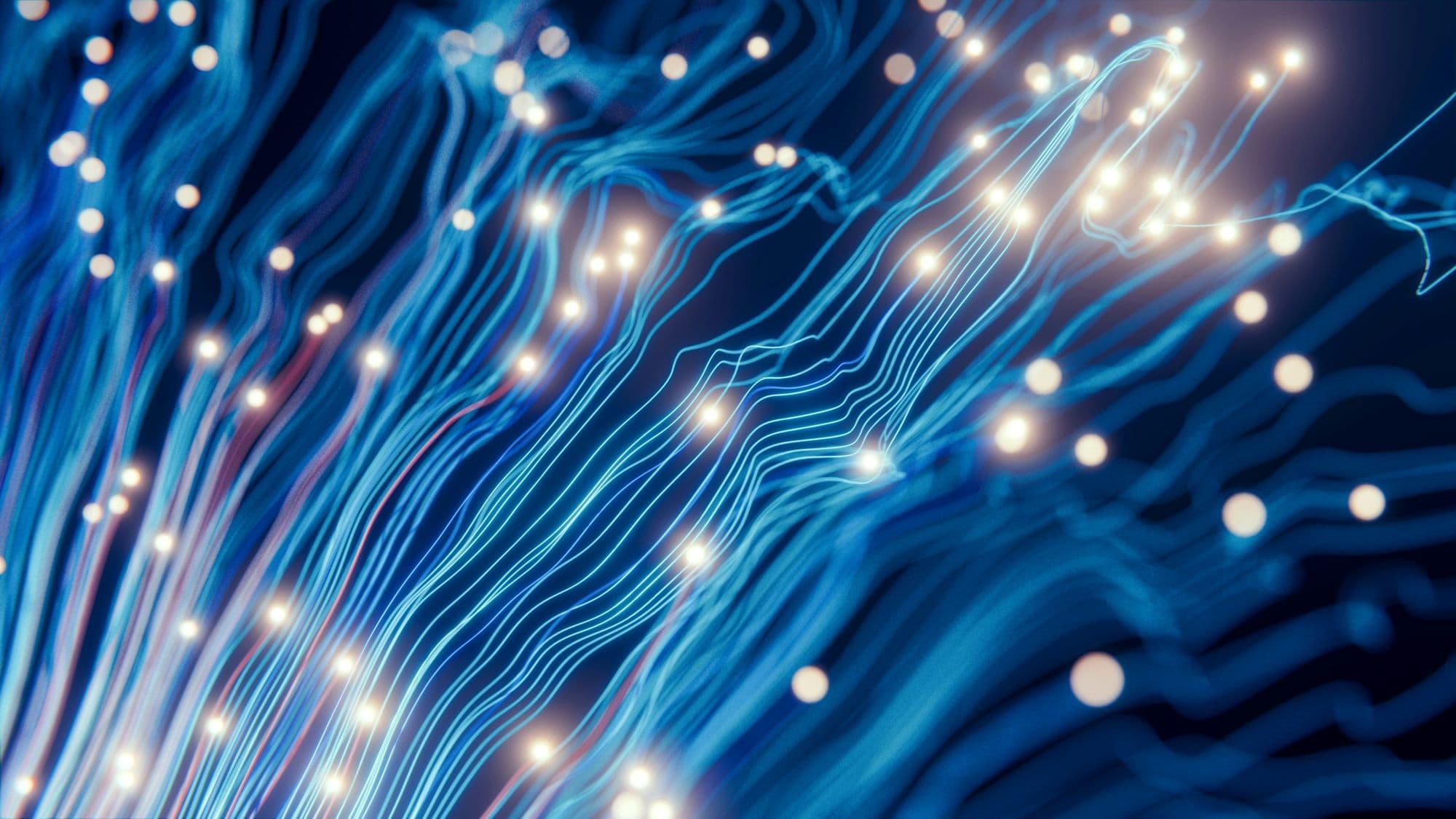 Close-up of glowing fibre-optic strands carrying light, representing interconnected intelligent systems
