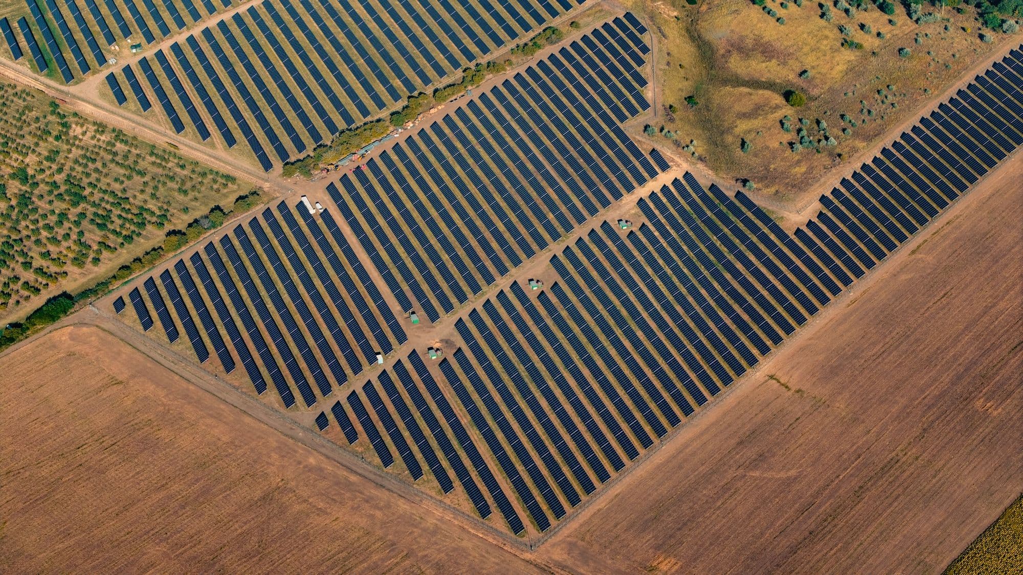 Aerial view of rows of solar panels across a large solar farm, representing sustainable energy infrastructure